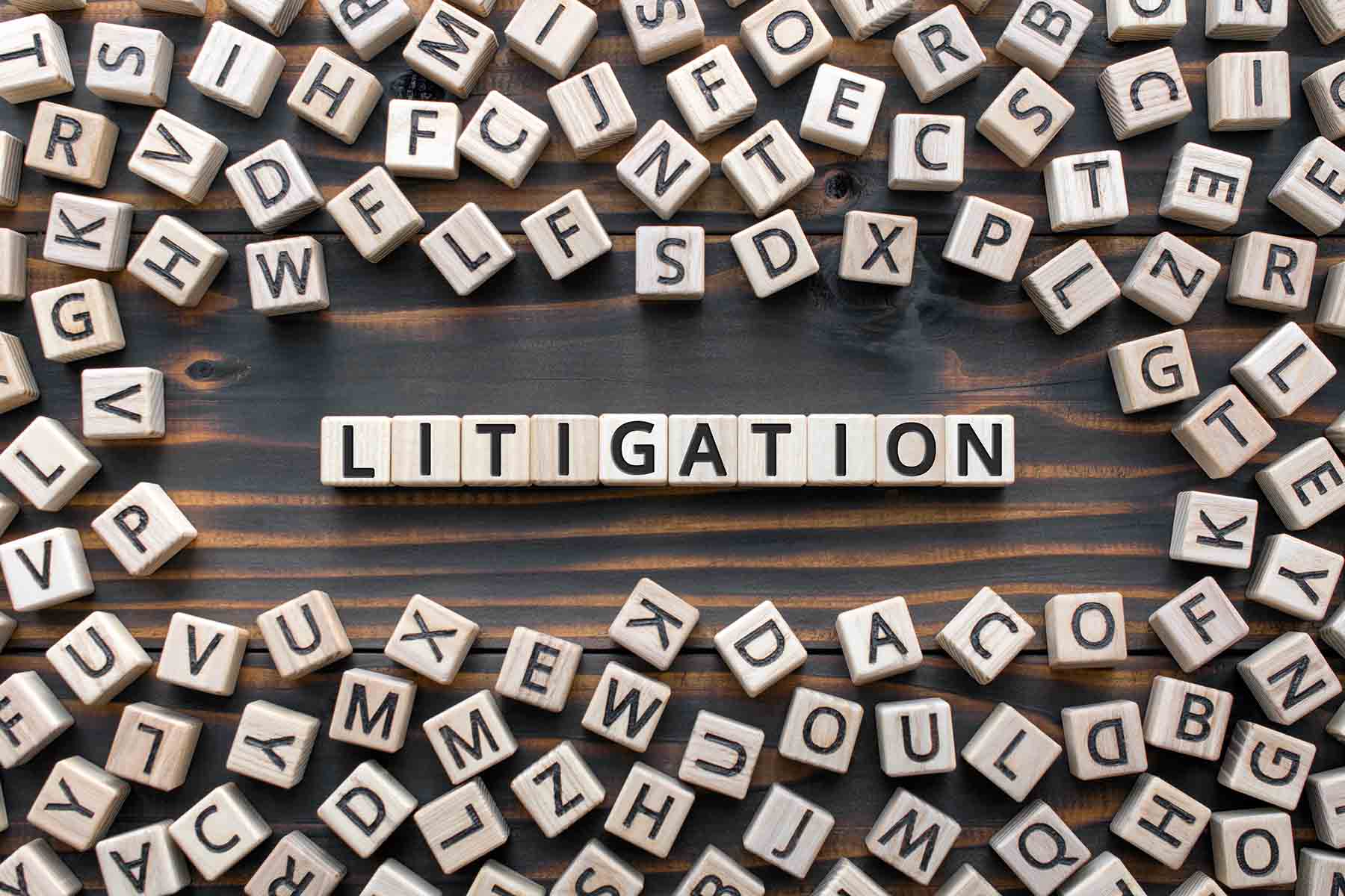 litigation - word from wooden blocks with letters, the process determining issues a court Arbitration and Litigation concept, random letters around, top view on wooden background
